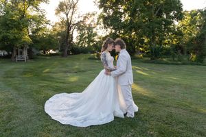 Bride and groom share a romantic moment on lush green lawn at golden hour wedding ceremony outdoors.