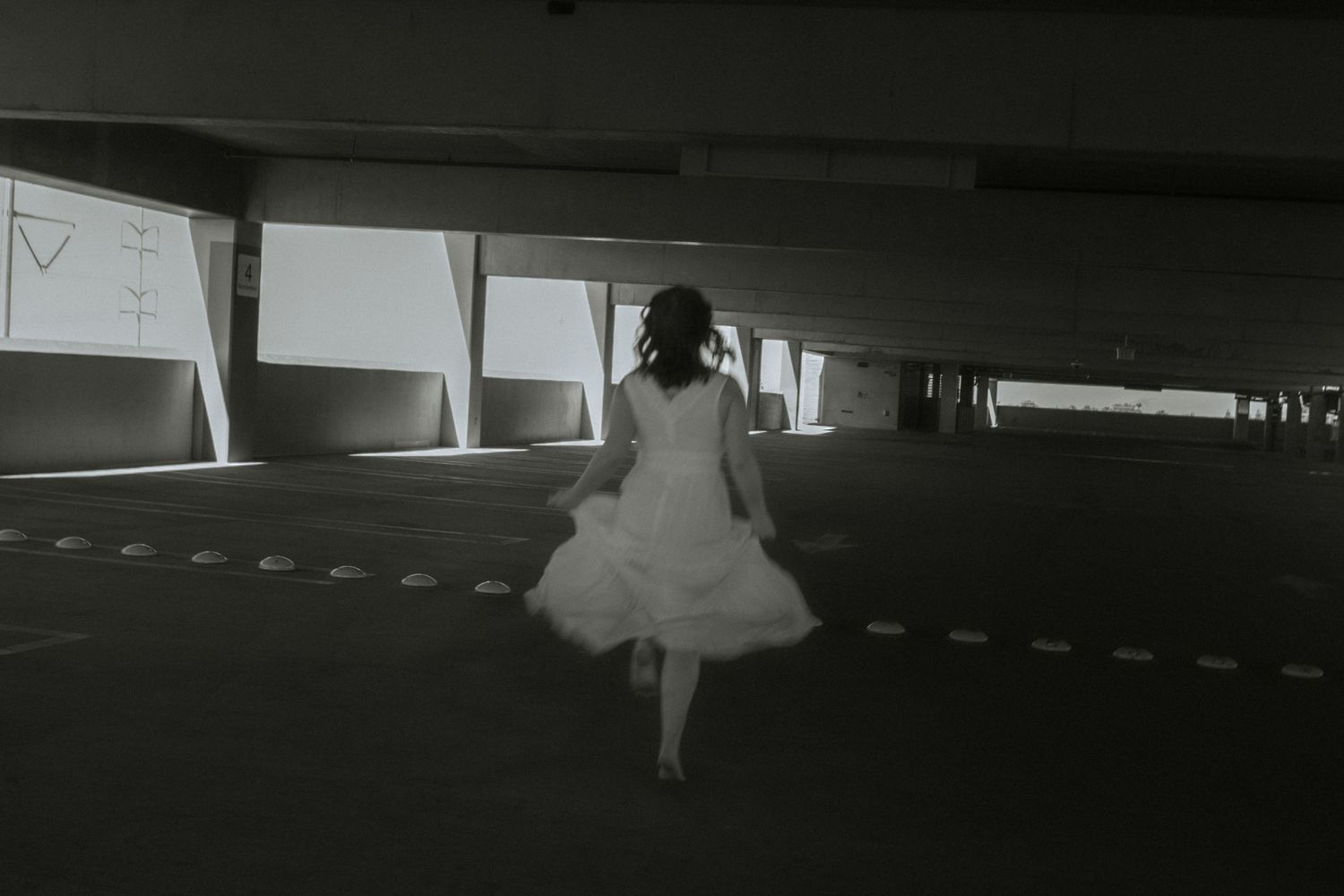 Moody black-and-white image of girl dancing in parking garage