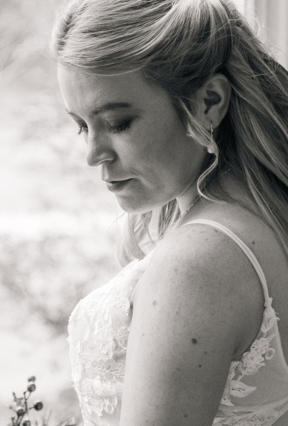 Black and white portrait of a bride in a lace dress with soft lighting and delicate details.