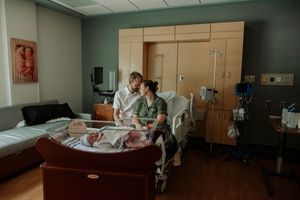 New parents admiring their newborn baby together in hospital room after delivery.