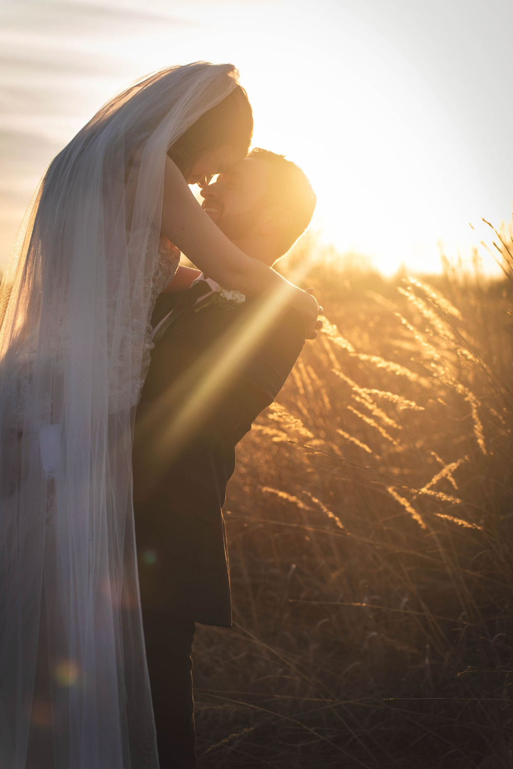 Cinematic golden hour moment with the couple in a field.