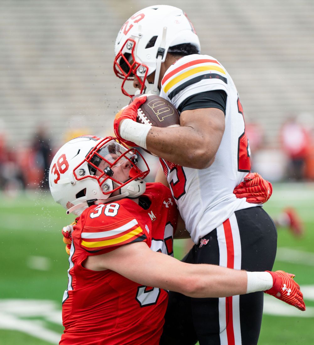Football players collide as one tackles the other during a game on the field.