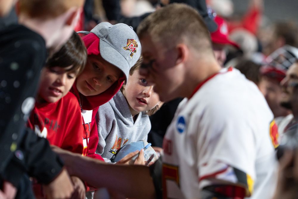 Baseball fans eagerly seek autographs from players before a game.
