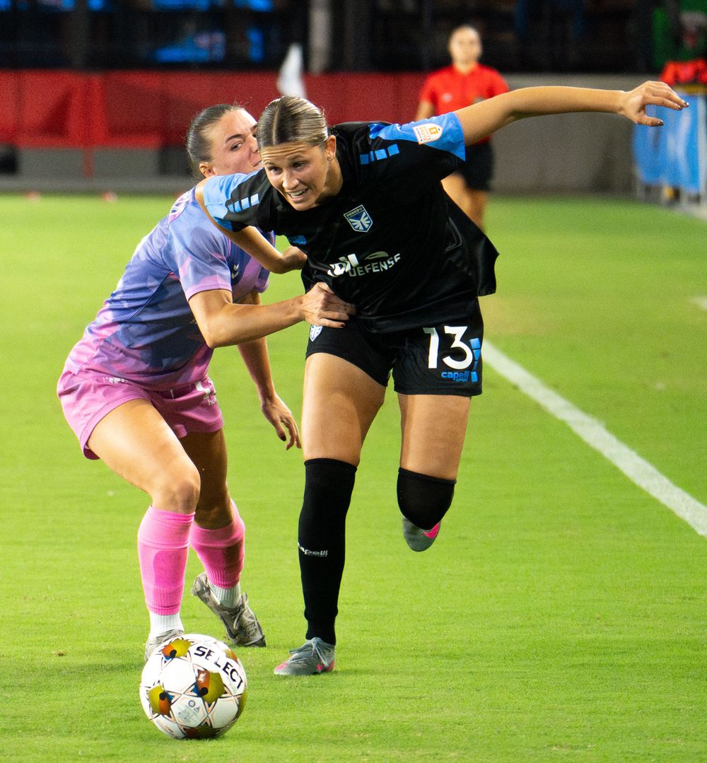 Soccer players compete for the ball during an intense match on a green field.