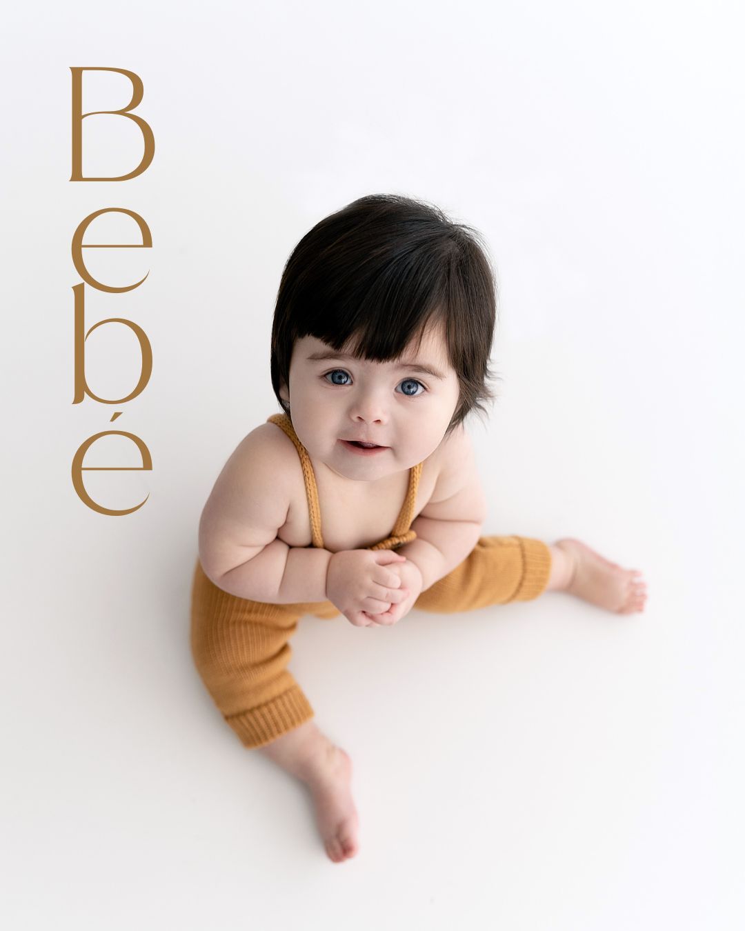 Baby in white onesie lying on white background.