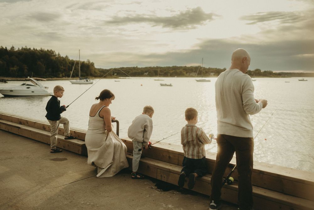 People fishing together along a wooden dock at dusk.