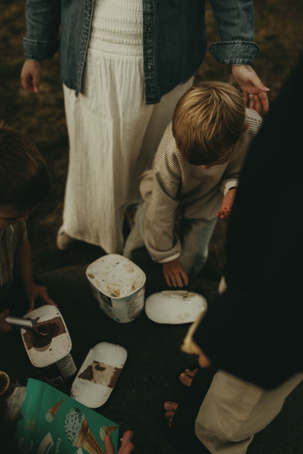 People examining items on ground during an outdoor gathering.