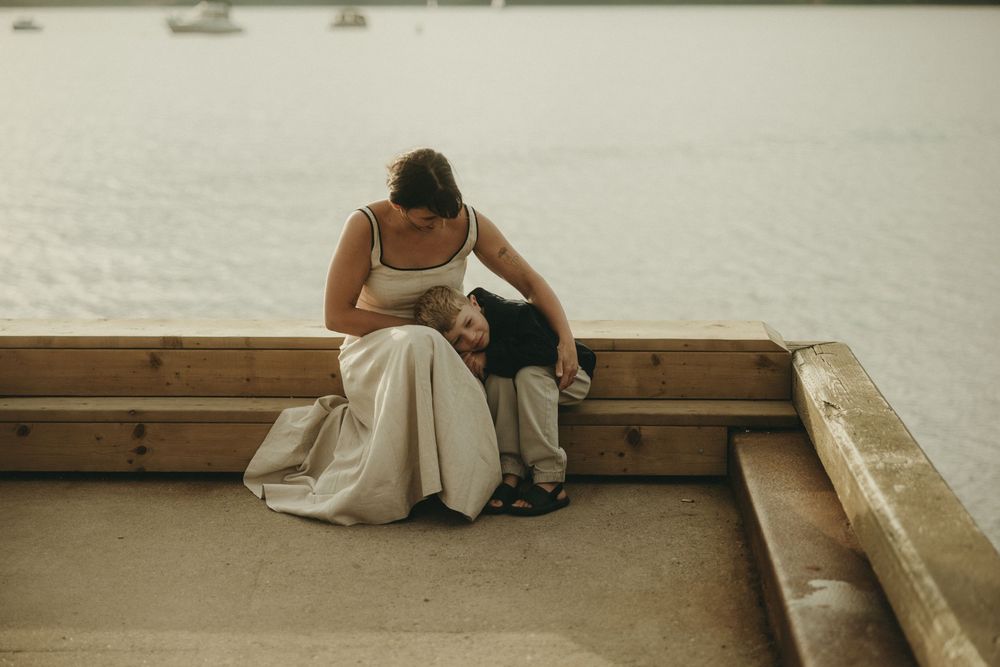 People relaxing on wooden benches overlooking a serene waterfront.
