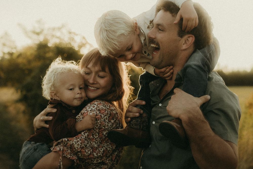 Family members embrace and share affectionate moments during sunset photoshoot.