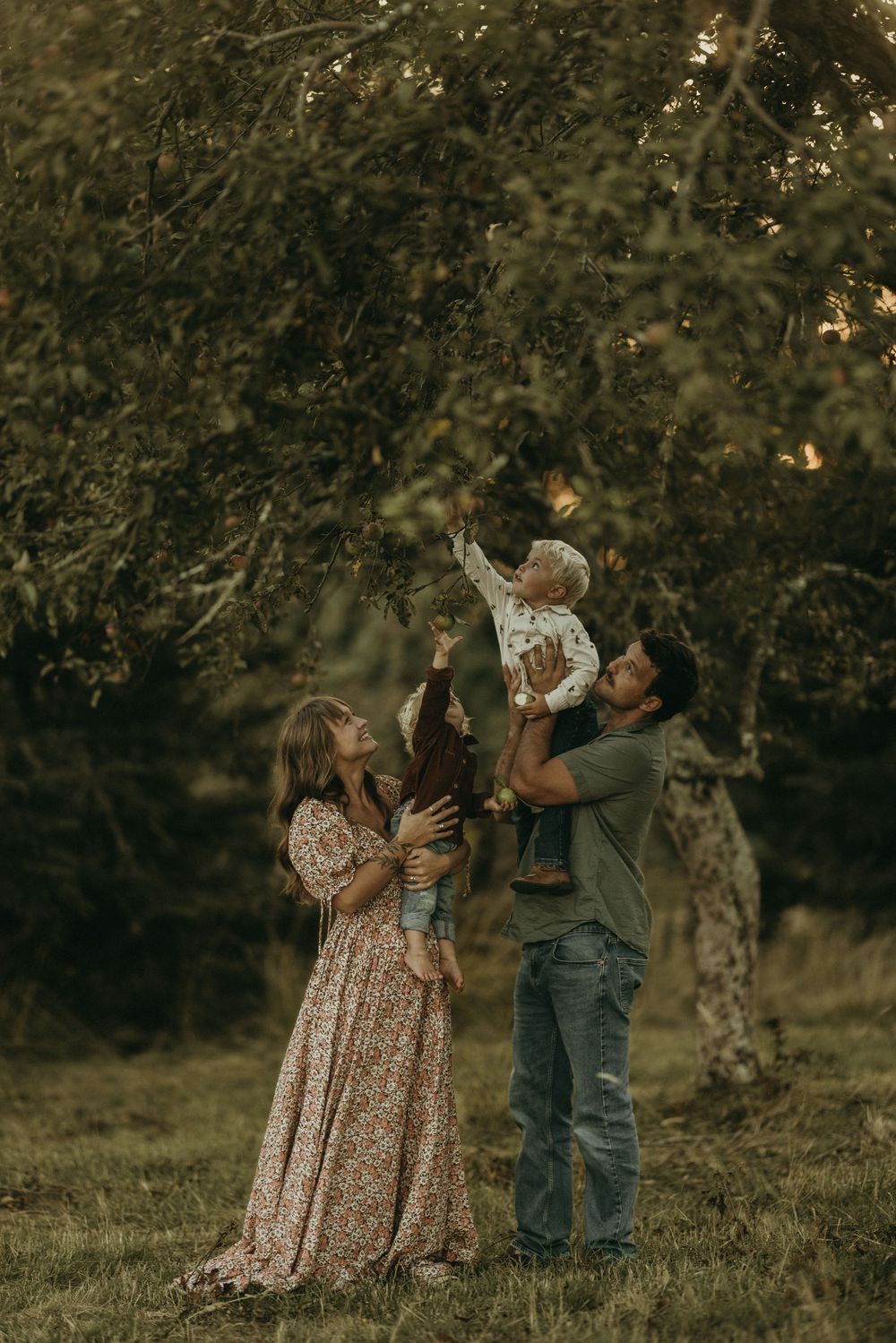 A family shares a joyful moment together under a blooming tree in a garden setting.