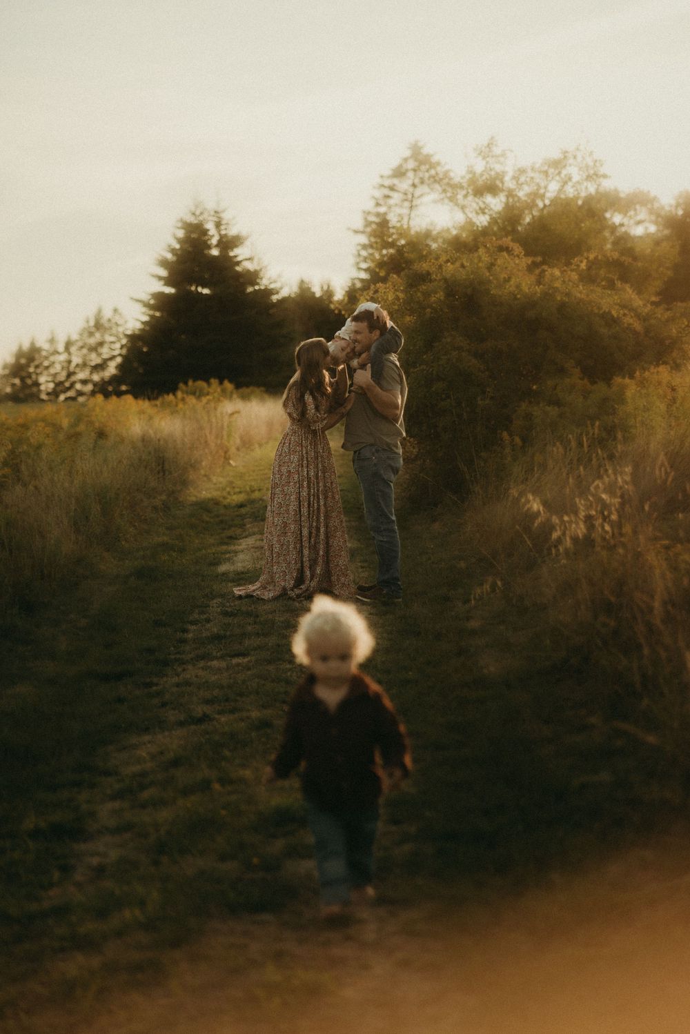 A family shares playful moments together on a hillside path at dusk.