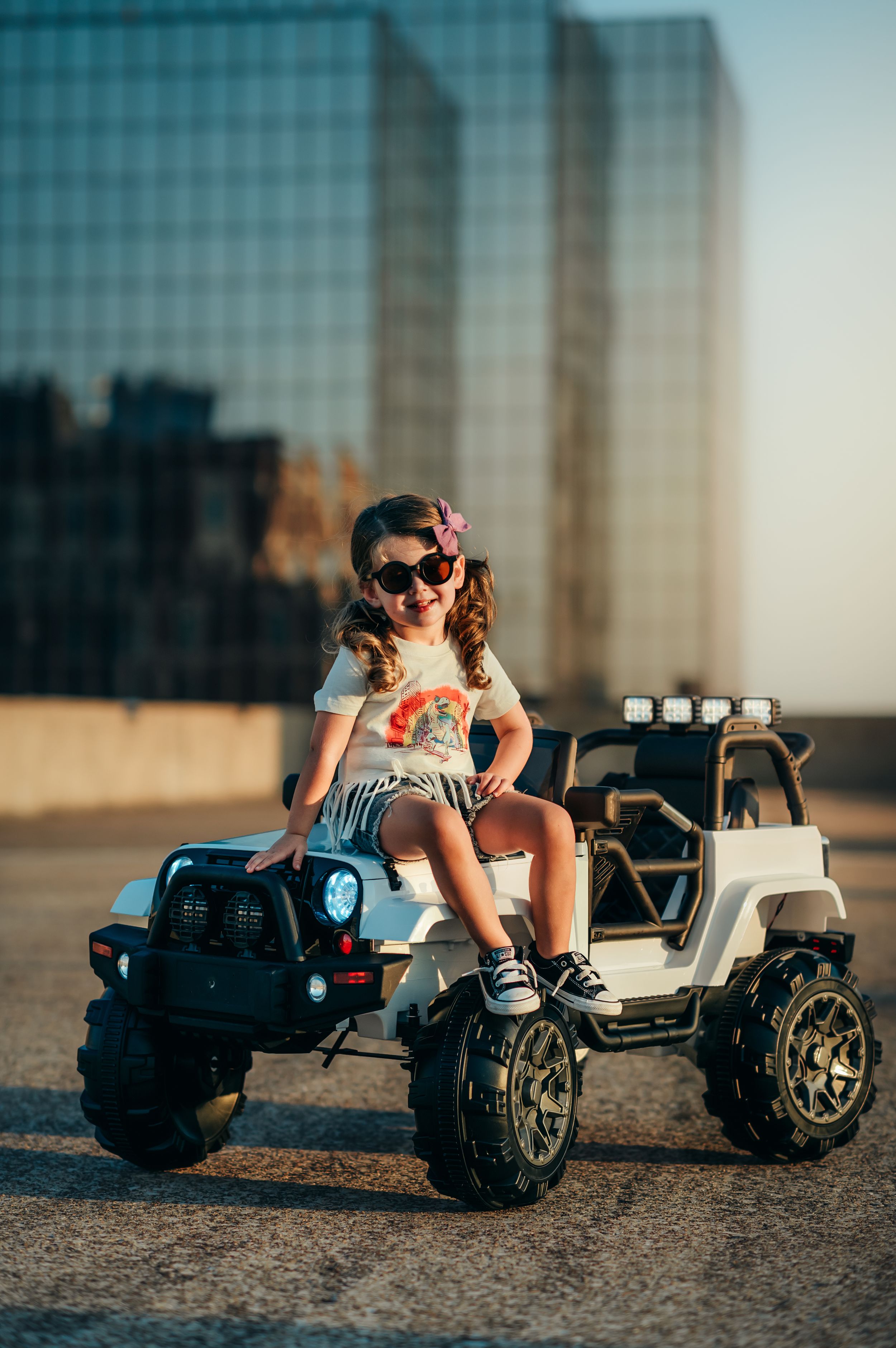cute 3 year old sits on hood of white toy jeep on top of parking garage in downtown chattanooga