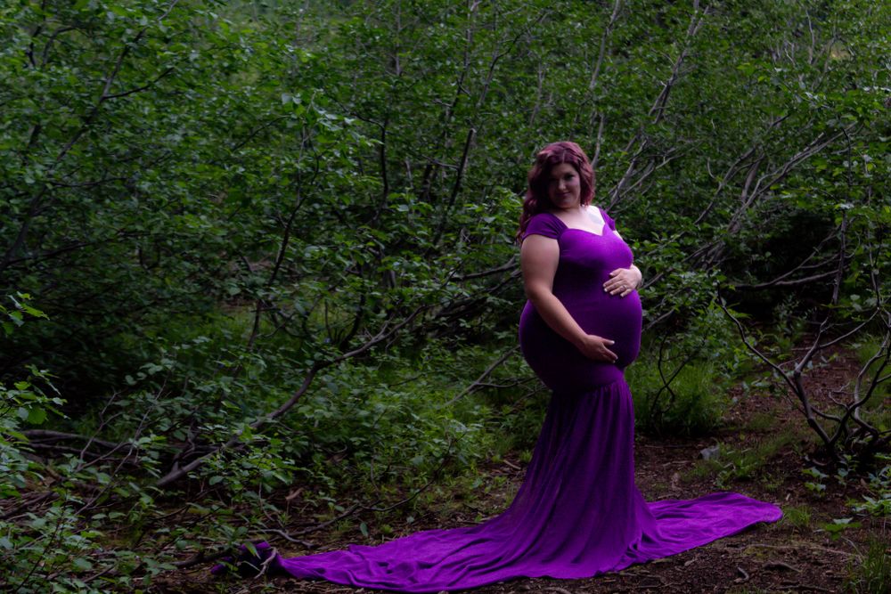 Purple dress flowing in a lush green forest setting during a photo session.