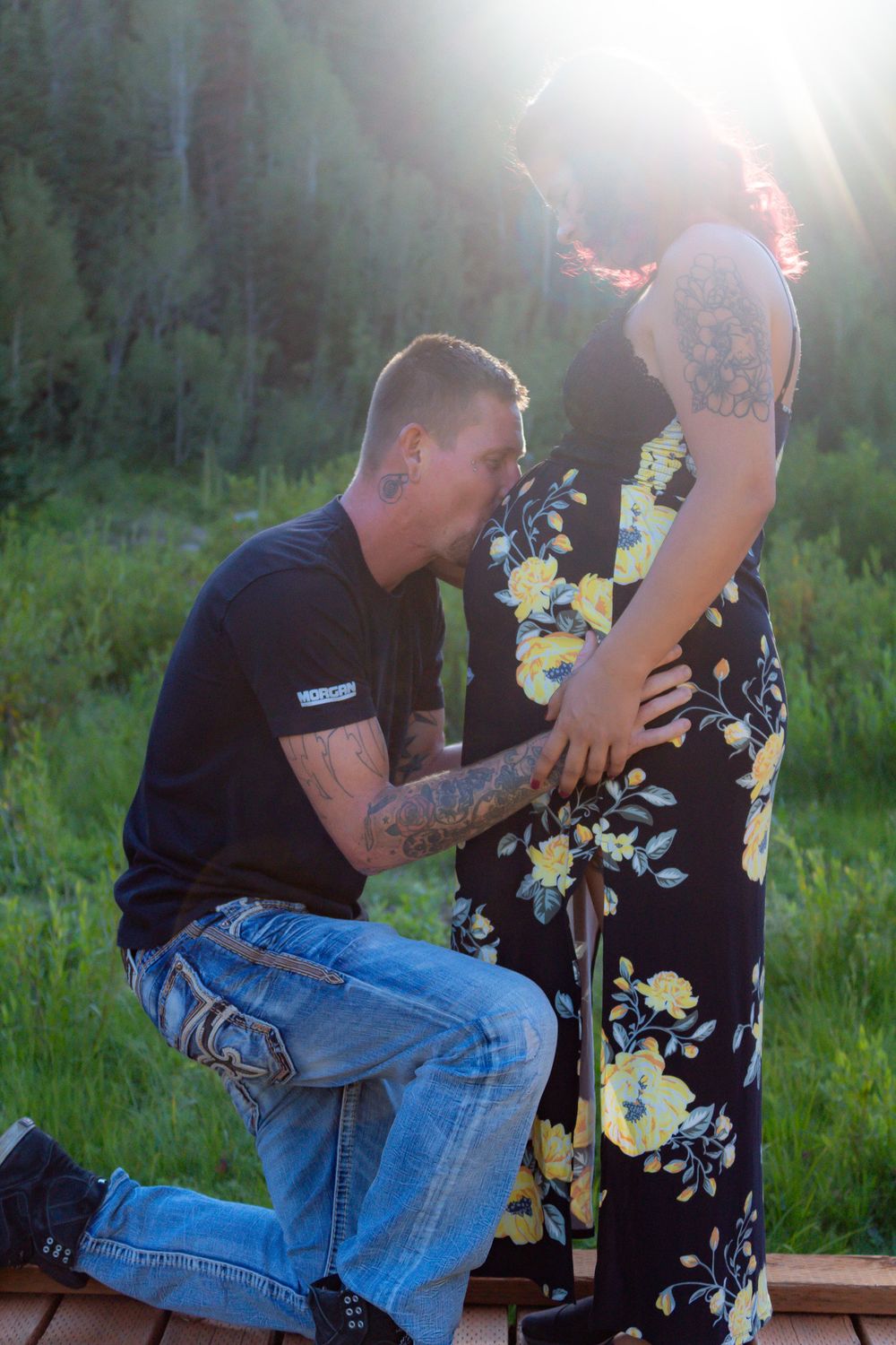 Romantic proposal moment captured on wooden deck with mountain sunset backdrop.