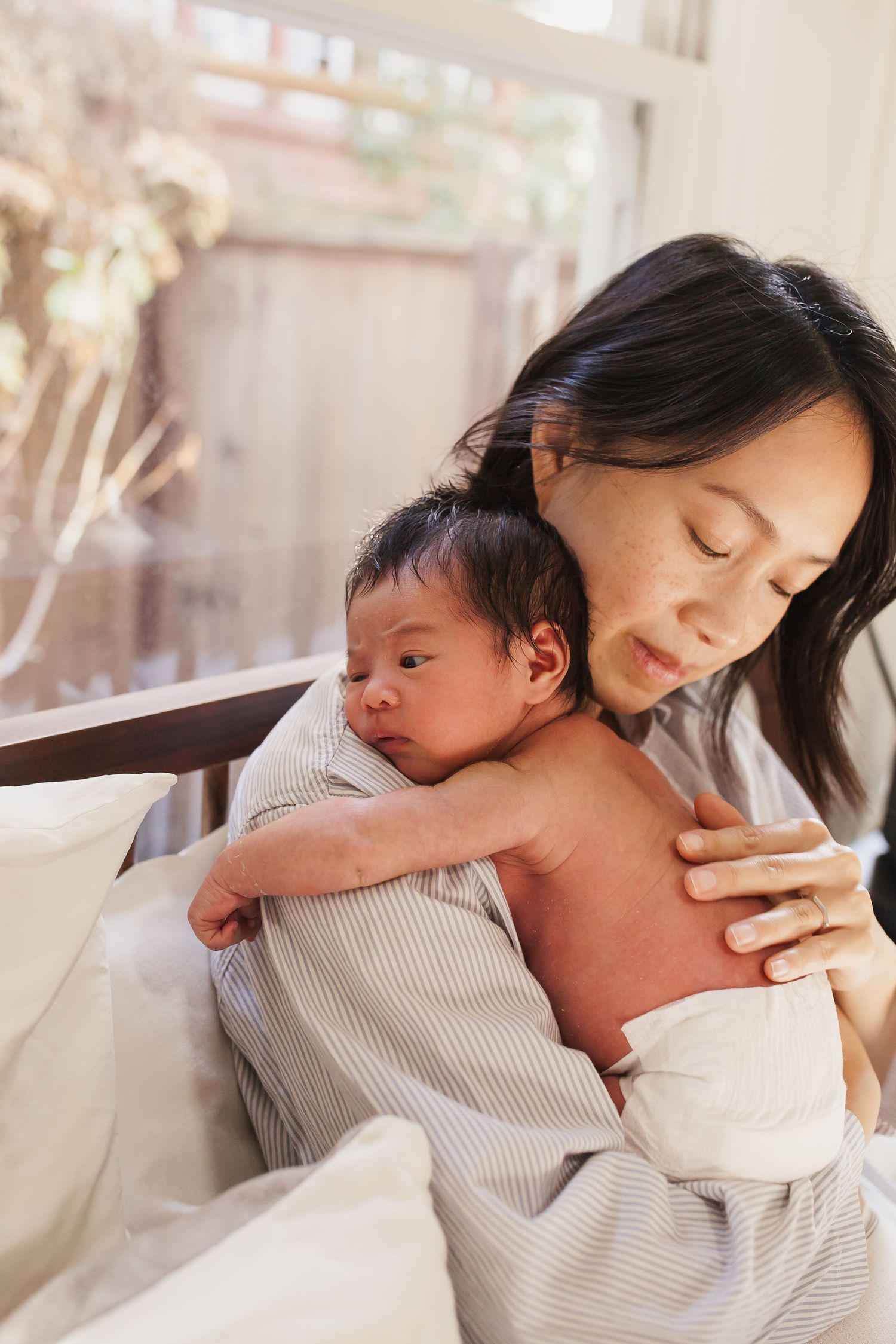 Close-up shot of hands tenderly holding a tiny baby's hand.