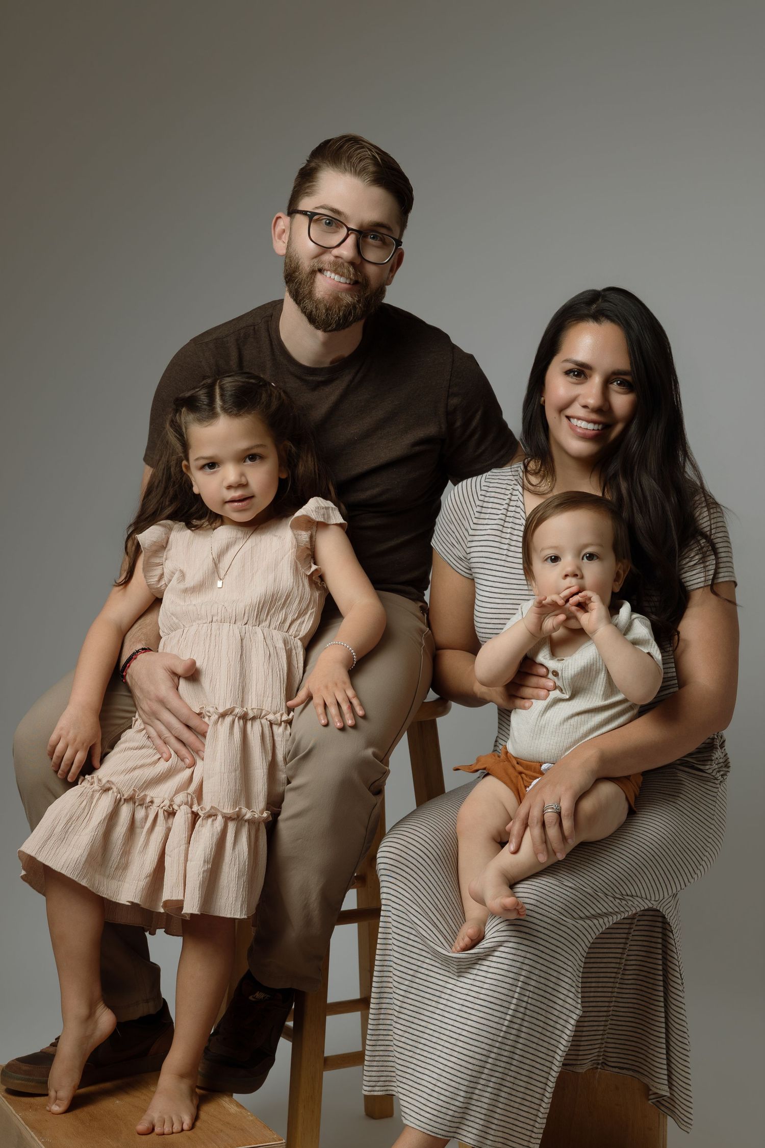 Maternity photo of couple in white against light background showing expectant mother's pregnant belly.
