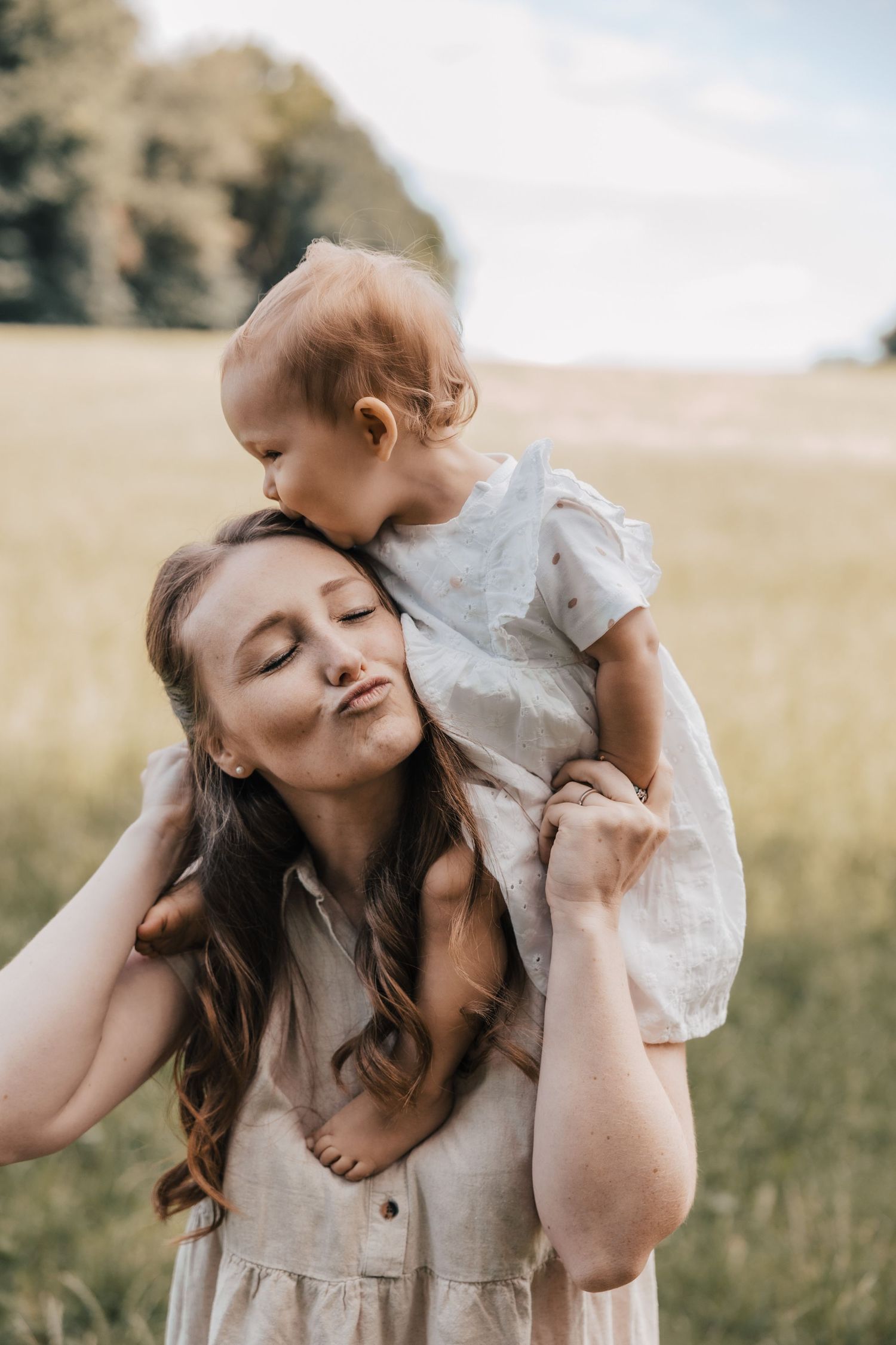 A tender outdoor photoshoot in a golden field with sweet embraces and natural light.
