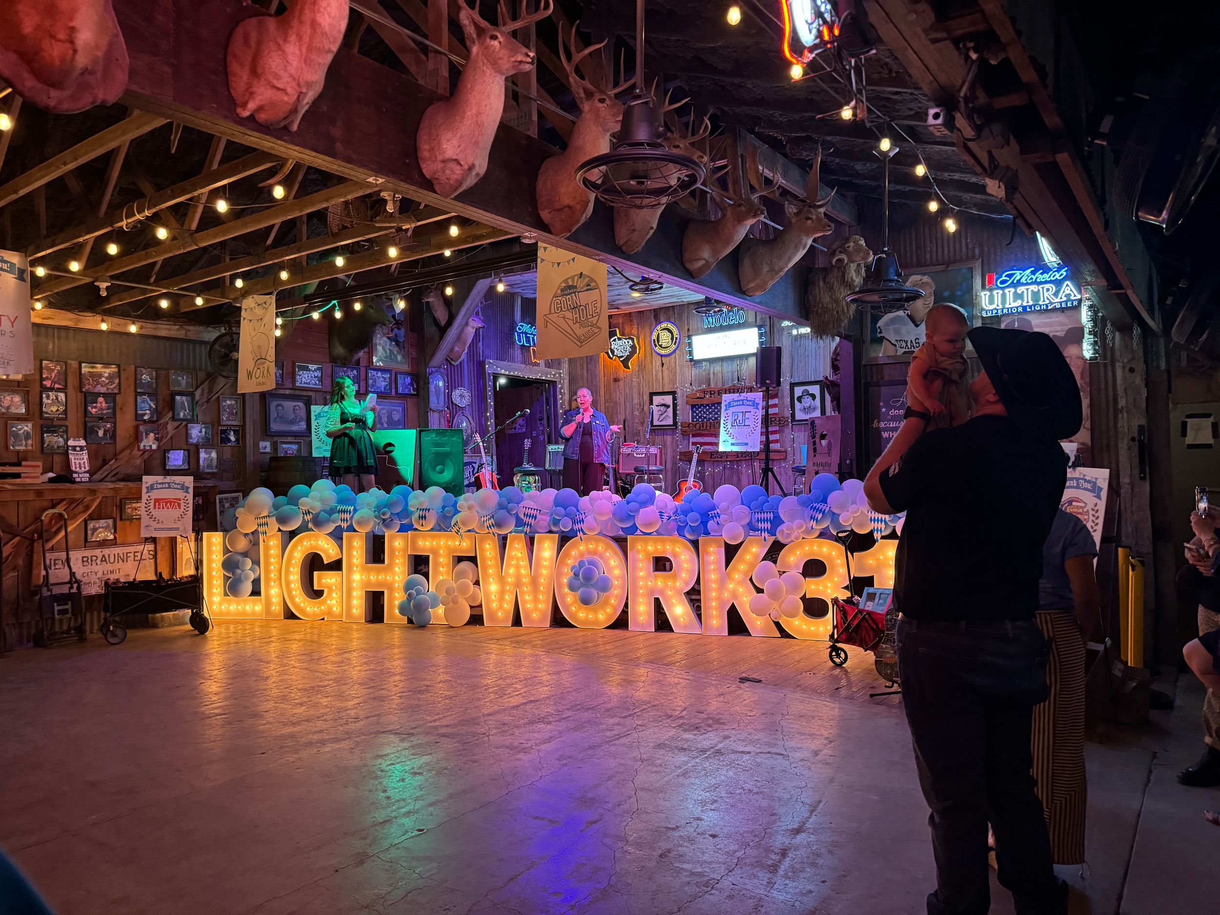 Illuminated LIGHTWORKS sign display inside a rustic venue with colorful lighting and taxidermy decor.