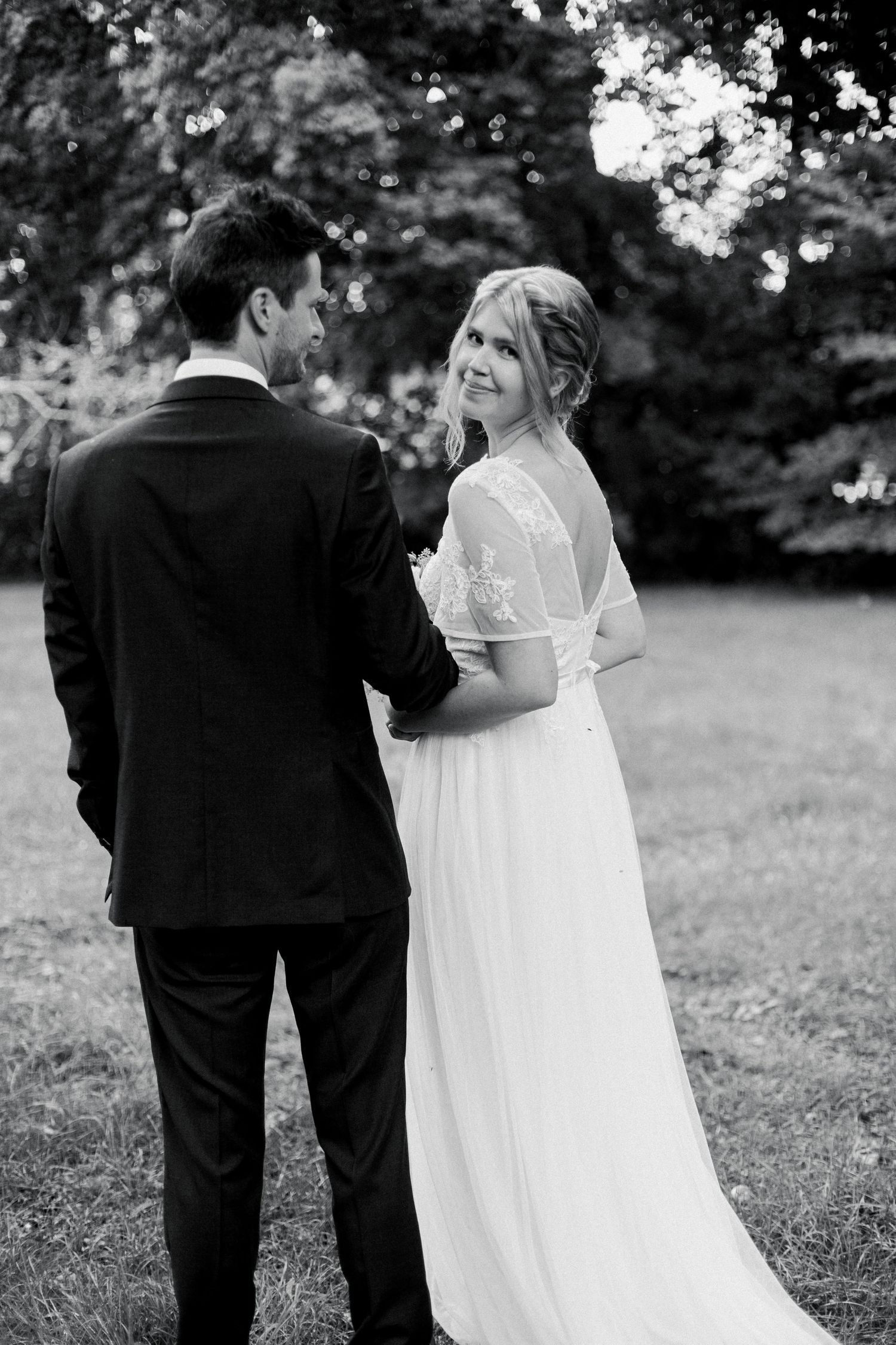 Couple in wedding attire sharing a tender moment outdoors in black and white.