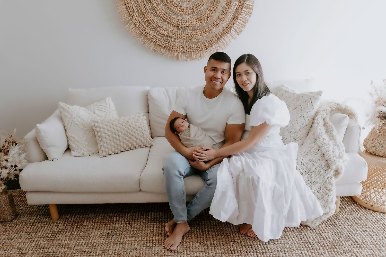 Family lounges together on white sofa with circular woven wall decor above.