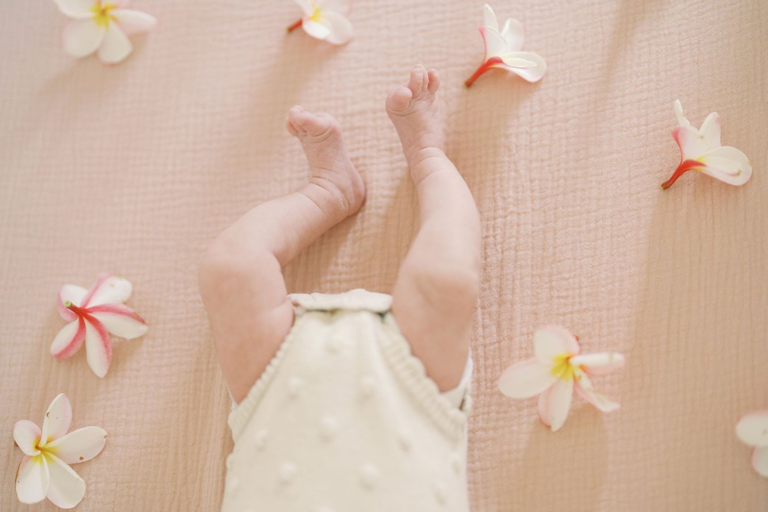 Newborn baby resting peacefully on white blanket.