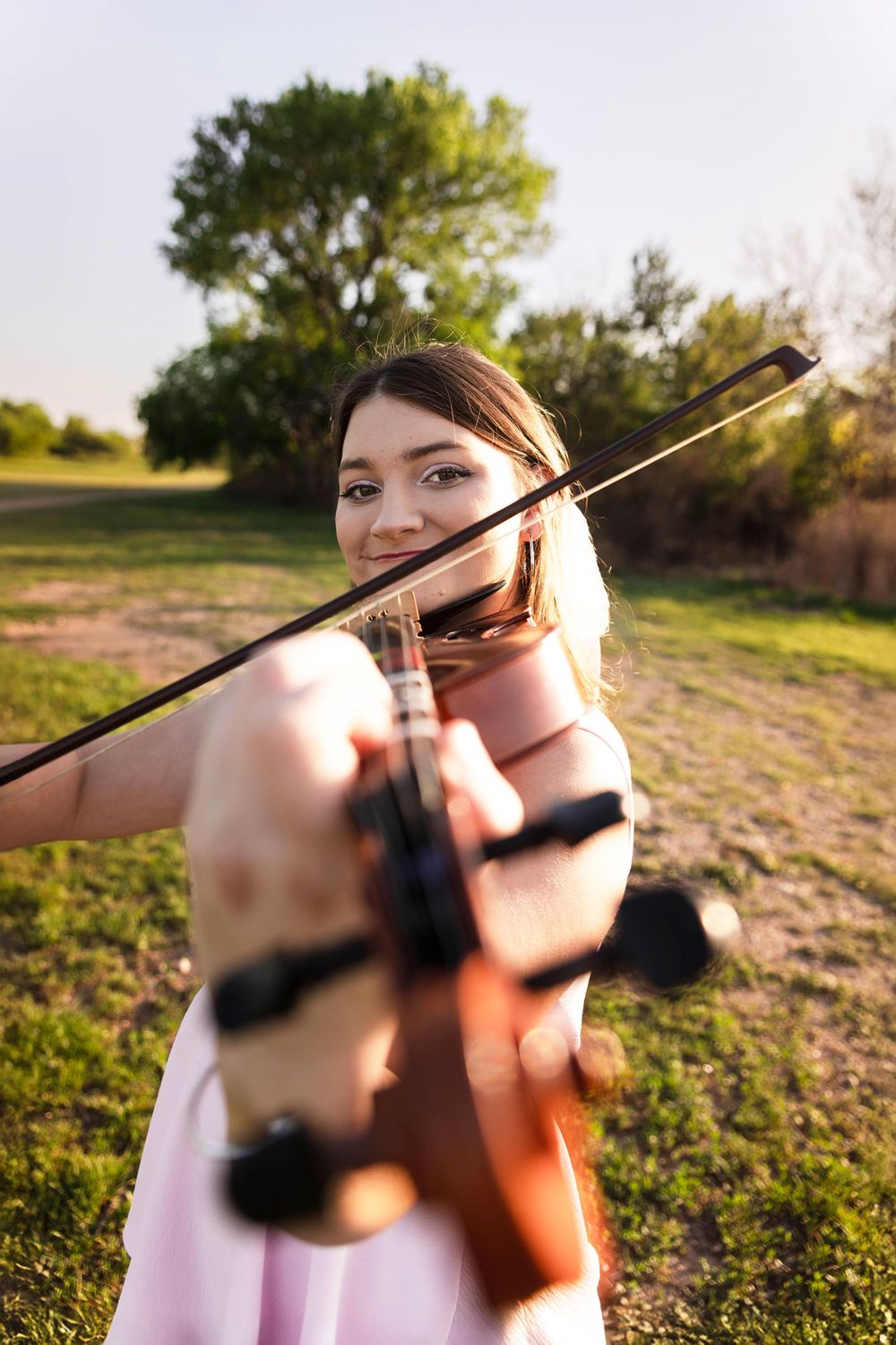 A young woman plays her violin in the park.
