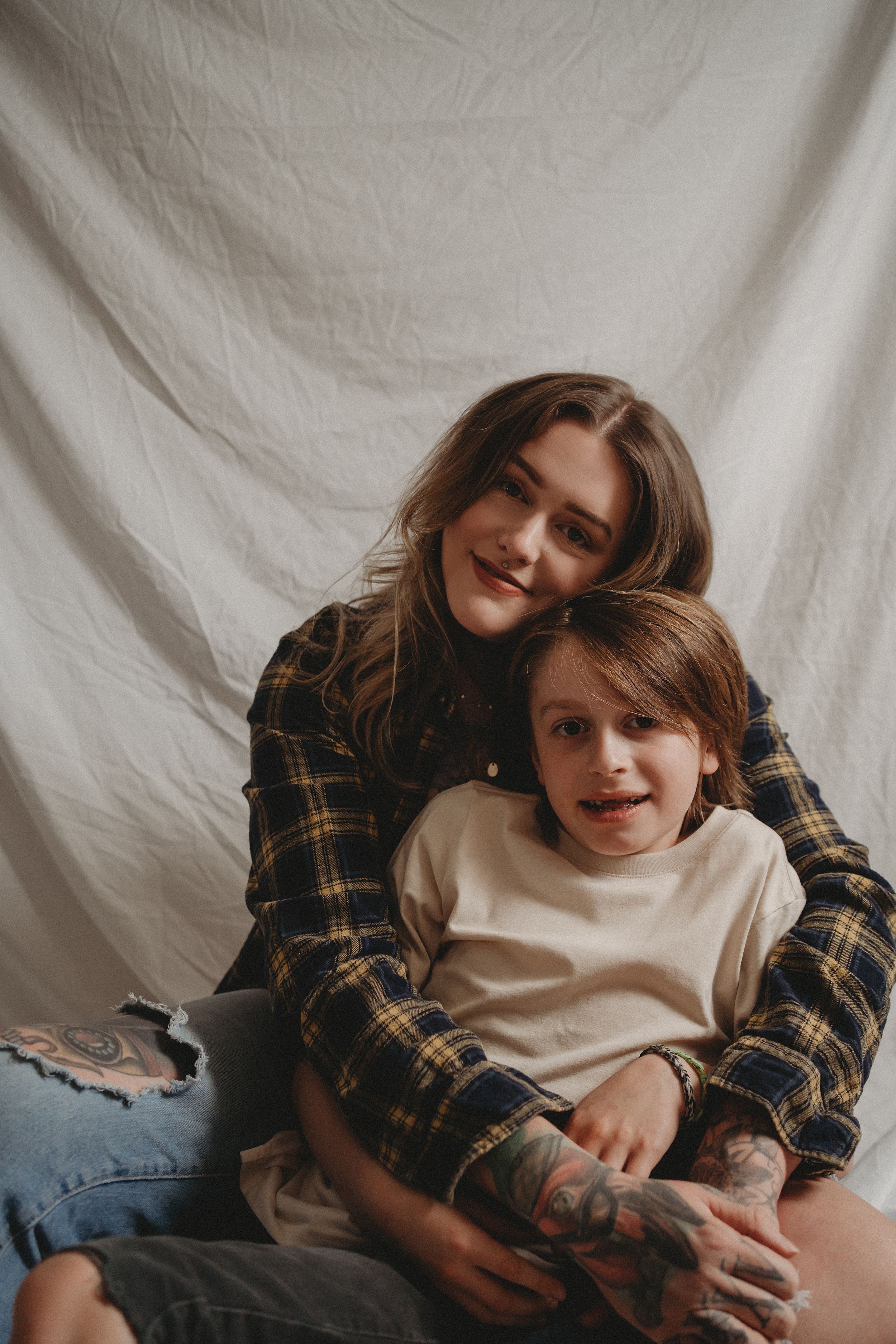 Tender lifestyle portrait of parent and child embracing against white backdrop.