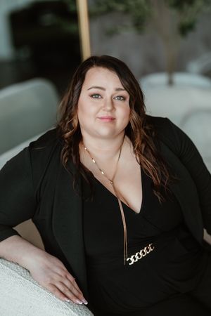 Professional portrait featuring a black blazer against a soft white background in an intimate boudoir setting.
