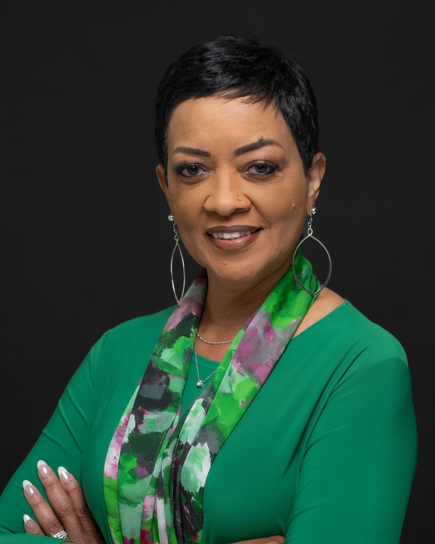 Confident woman in green top and patterned scarf posing for a professional headshot