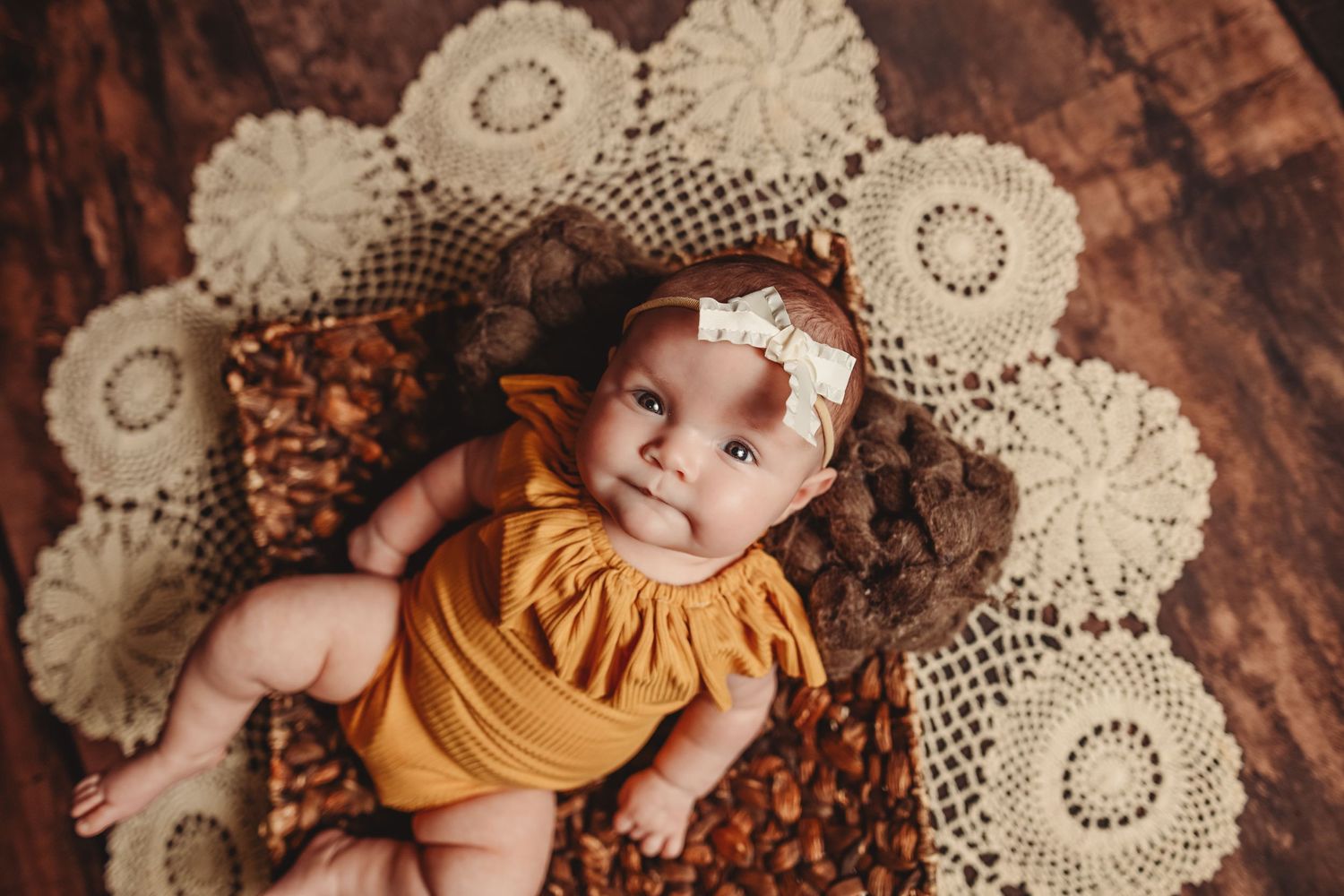 Vintage-style baby portrait on delicate lace doilies with mustard yellow romper.