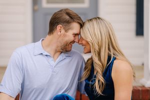 A couple shares an intimate moment together, touching foreheads while smiling outdoors.