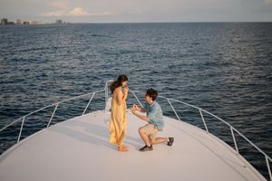 A couple enjoys a romantic sunset moment on a luxury yacht sailing across calm ocean waters.
