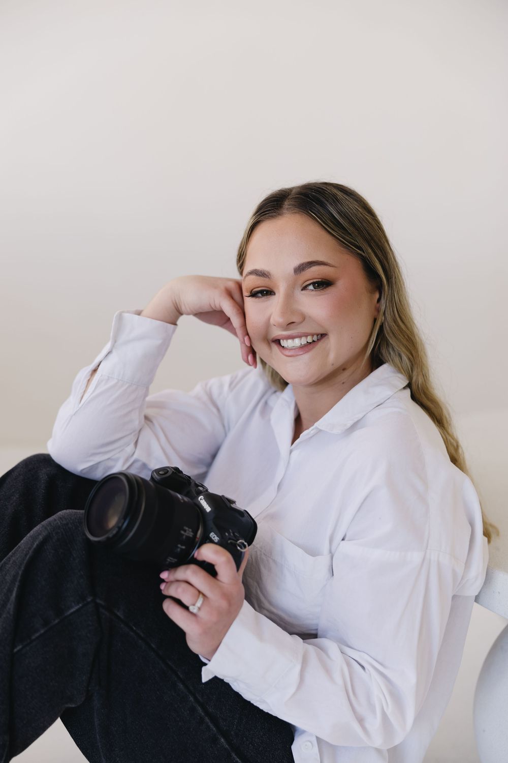 A person in a white button-down shirt holds a black cat while posing against a neutral background in a photo series.