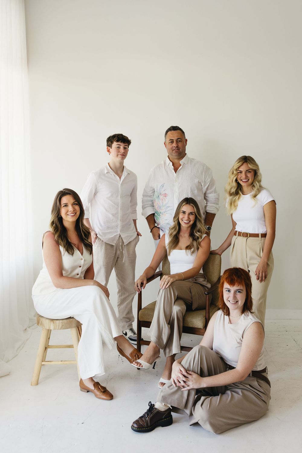 Professional studio portrait of team members in coordinated neutral outfits against white background.