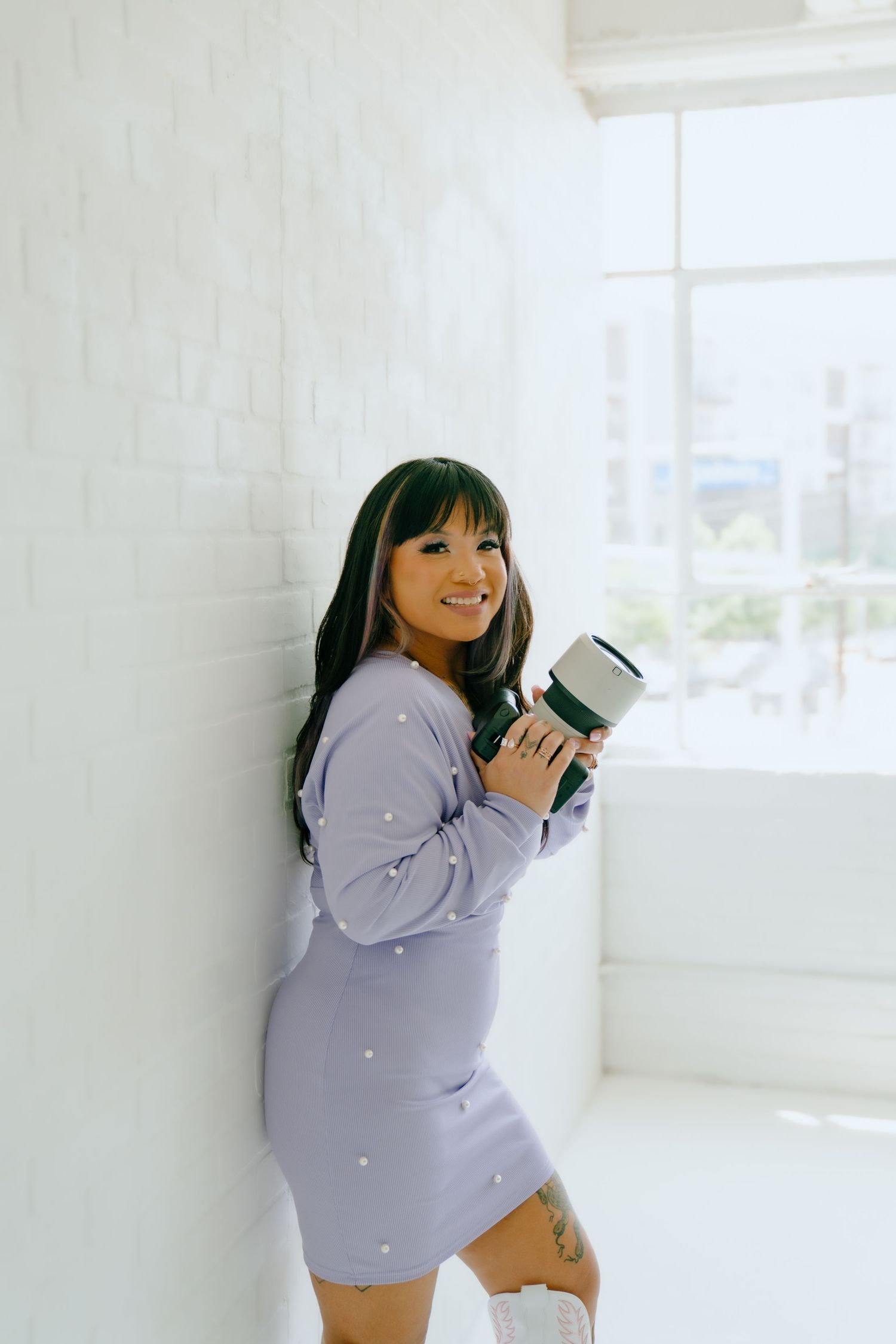 Lifestyle portrait of photographer holding coffee cup against bright white minimal interior.