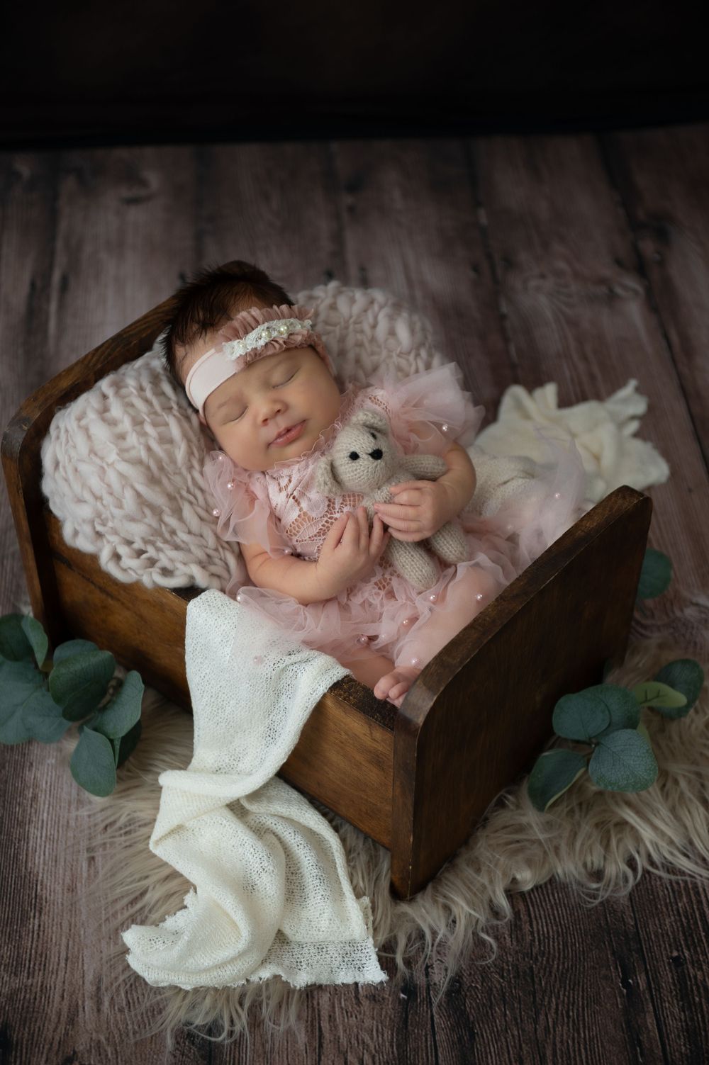 Vintage-style newborn photography with delicate lace details and wooden props.