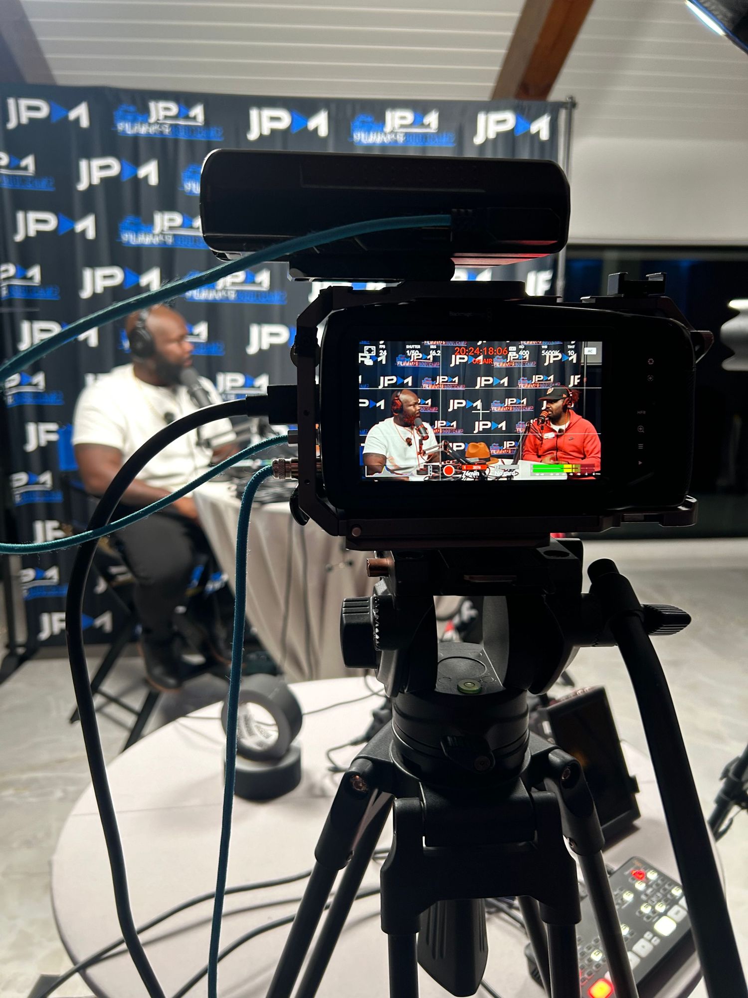 Video camera recording a sports interview with branded backdrop visible in frame.