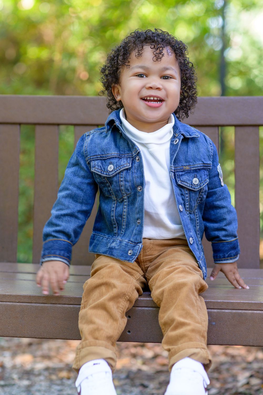 "Adorable little boy smiling brightly during a photoshoot, capturing pure joy and innocence in a heartwarming moment."