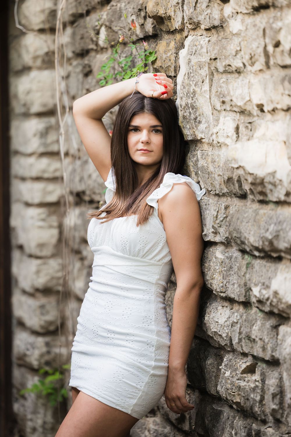 Portrait series showing someone in a white dress posing against a textured stone wall with dramatic lighting.