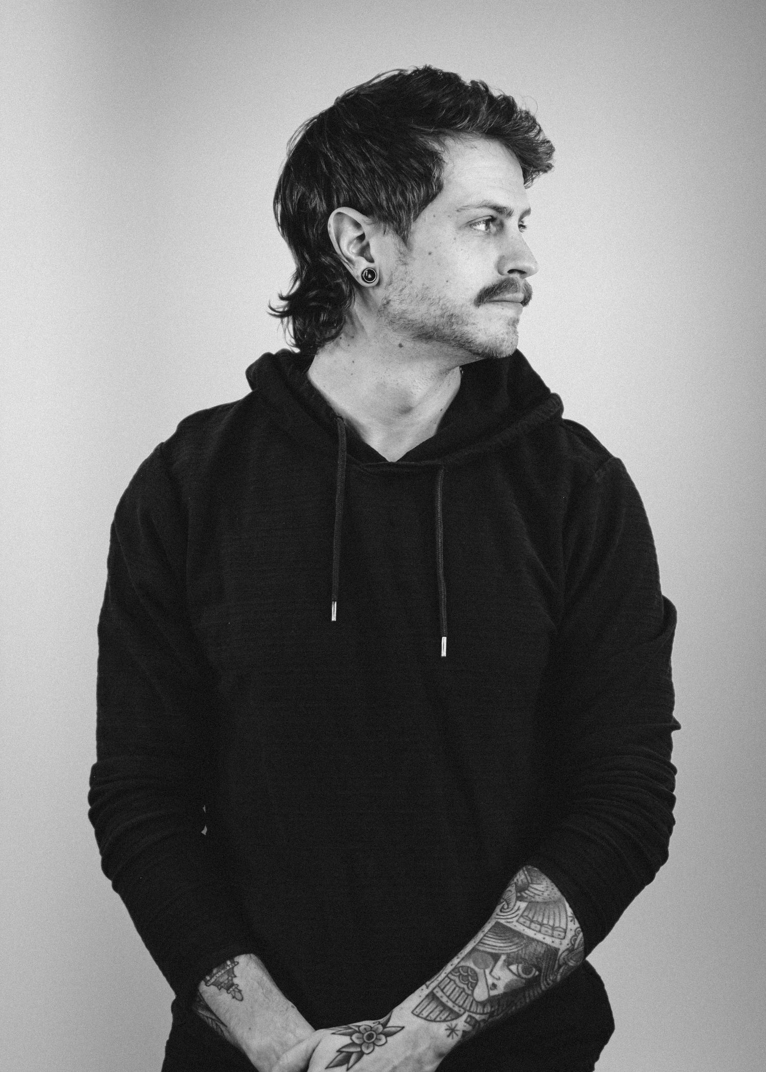 Black and white portrait of person in black hoodie looking to the side.
