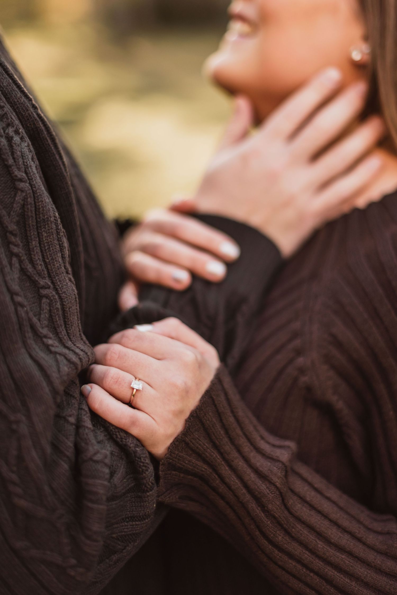 Couple in formal attire posing together at sunset in outdoor setting.