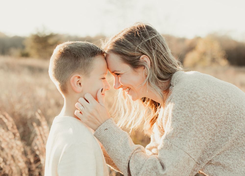 Mother and child sharing tender moment in golden sunlight.