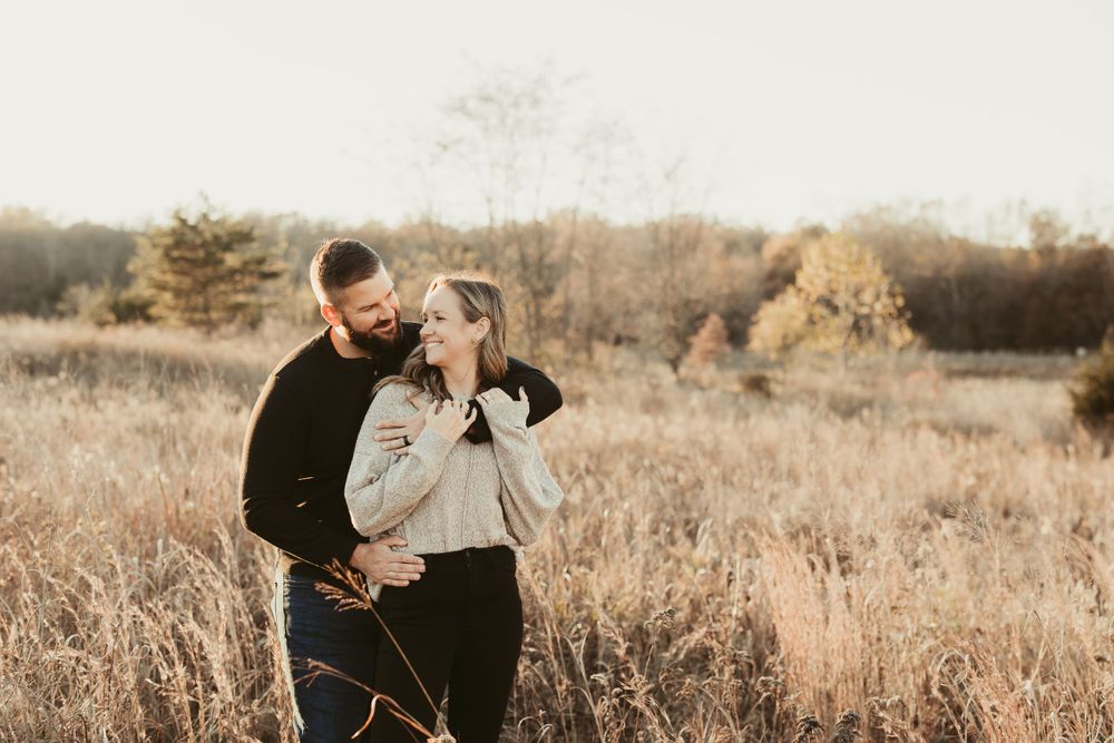 Couple embracing in golden field during sunset.