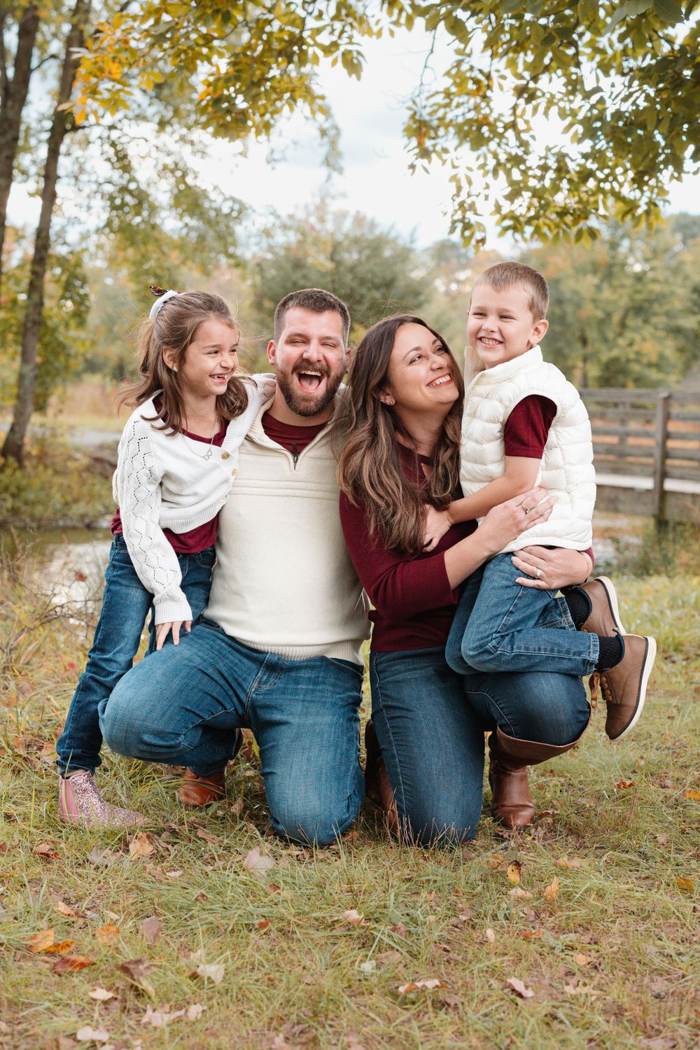 Happy family of four laughing together outdoors in autumn setting.
