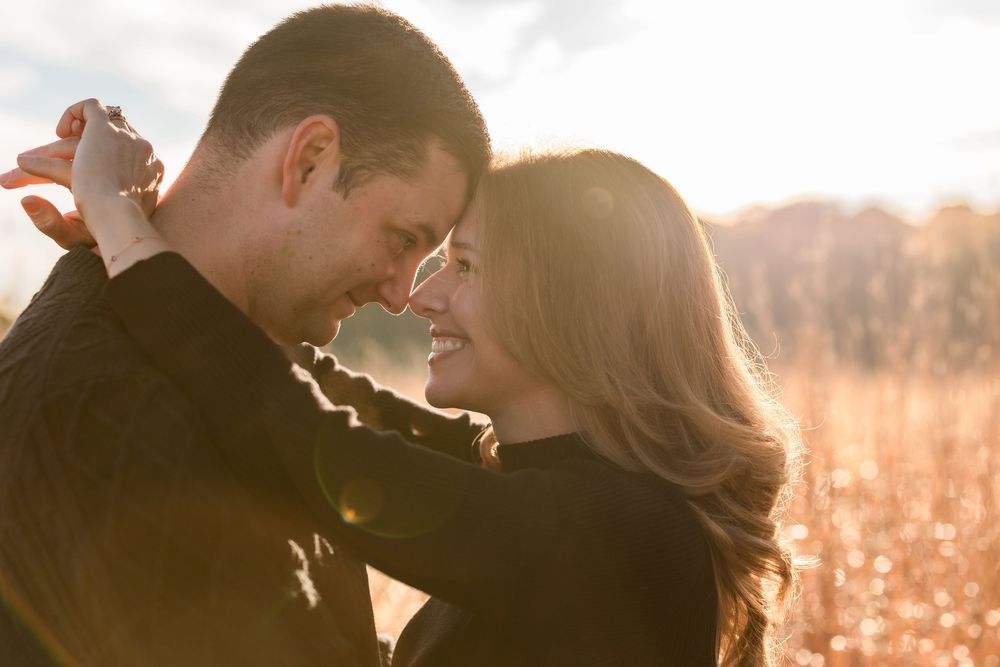A silhouetted couple embraces in a romantic sunset moment with golden light glowing behind them.