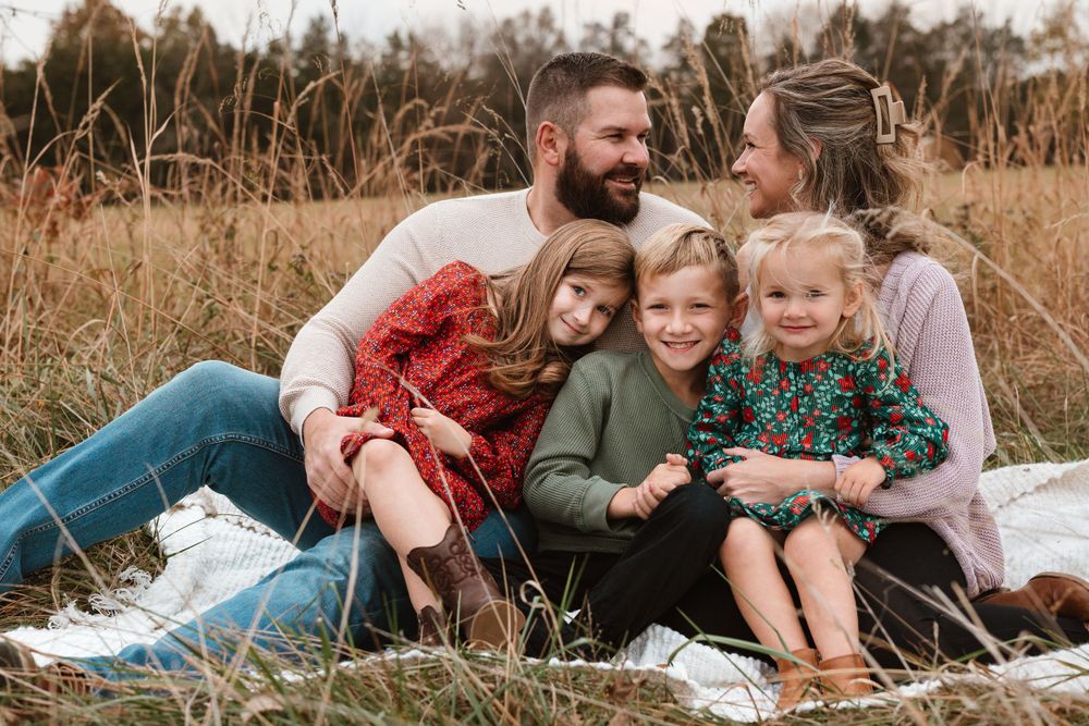 Family enjoying a cozy picnic together on a blanket in autumn field.
