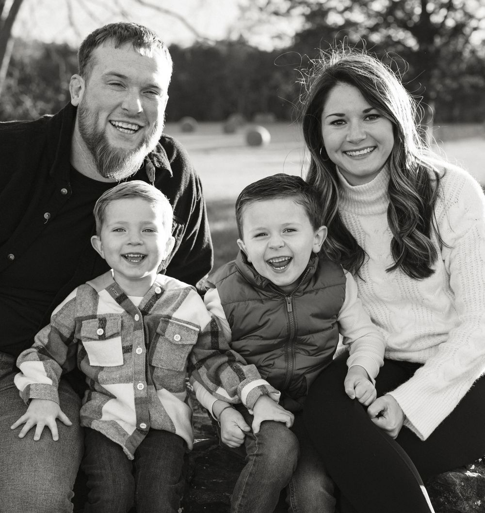Happy family of four poses together for outdoor portrait in casual attire.