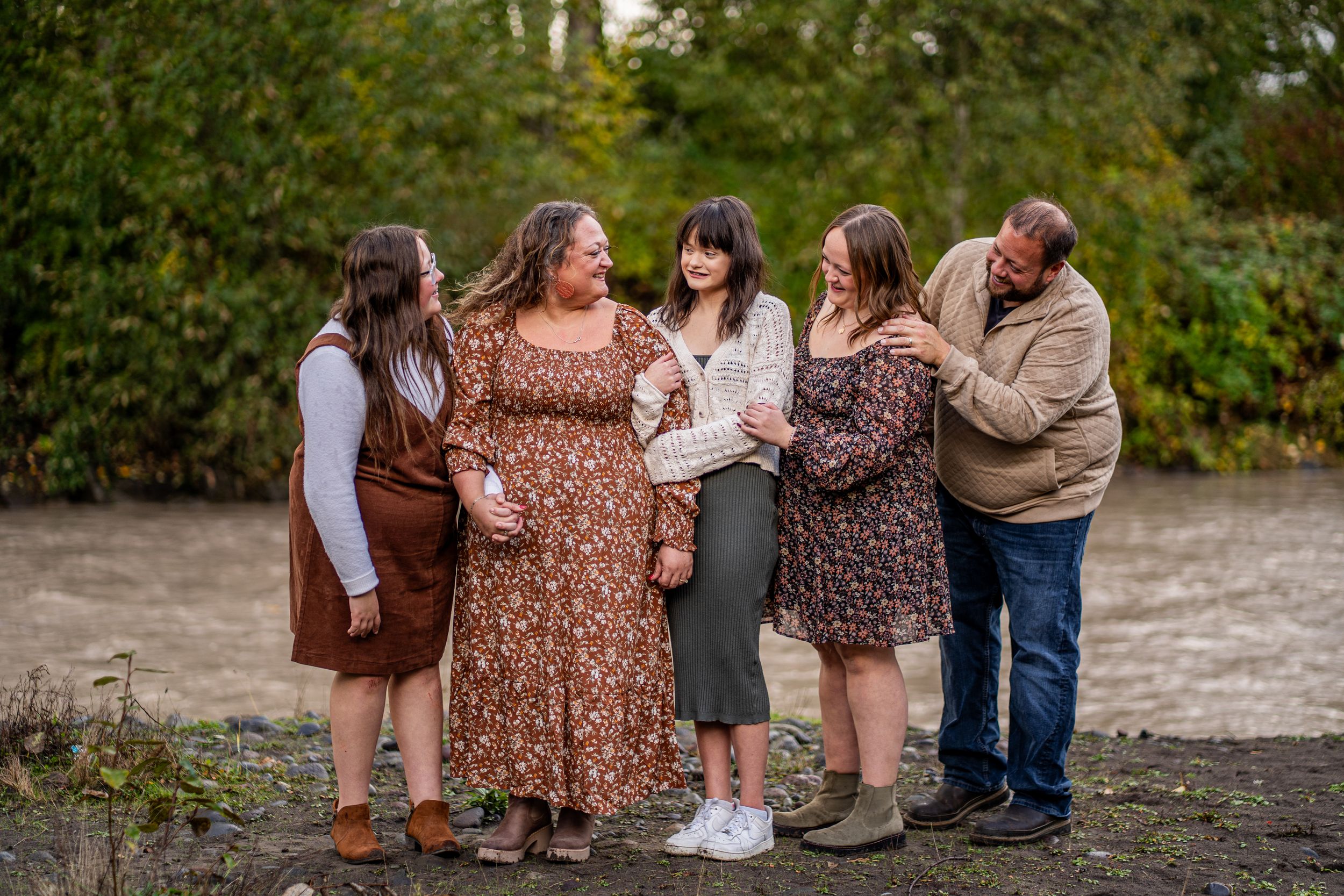A group in floral dresses and casual attire gathers outdoors for a photoshoot on a sunny autumn day.