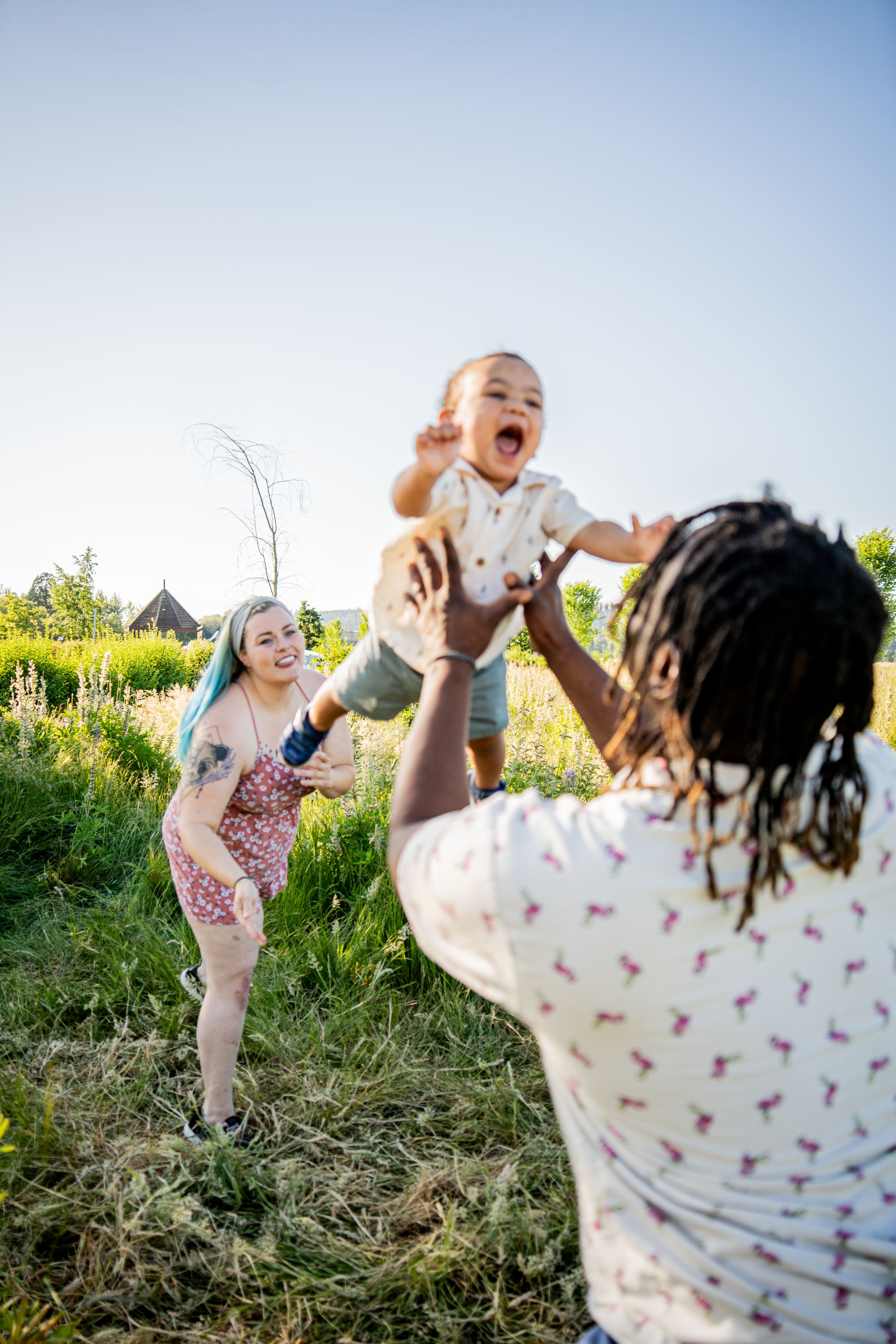 A joyful outdoor scene in a grassy field with people playing and laughing together on a sunny summer day.