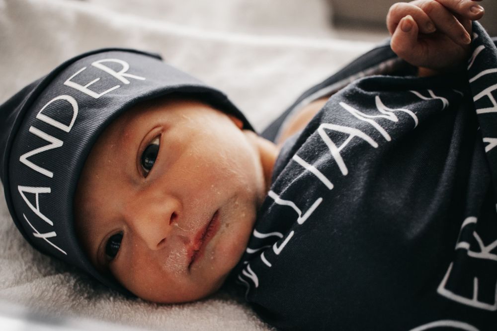 A newborn baby observing his parents from his hospital bassinet.